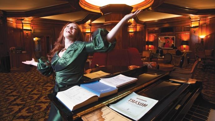 Sarah Davis sings Mozart with arms outstretched in an elegant hotel lobby